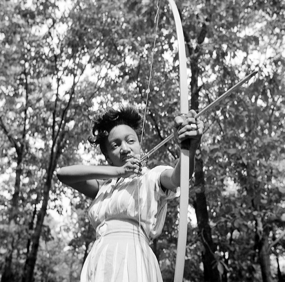 black and white photo of a woman shooting a bow