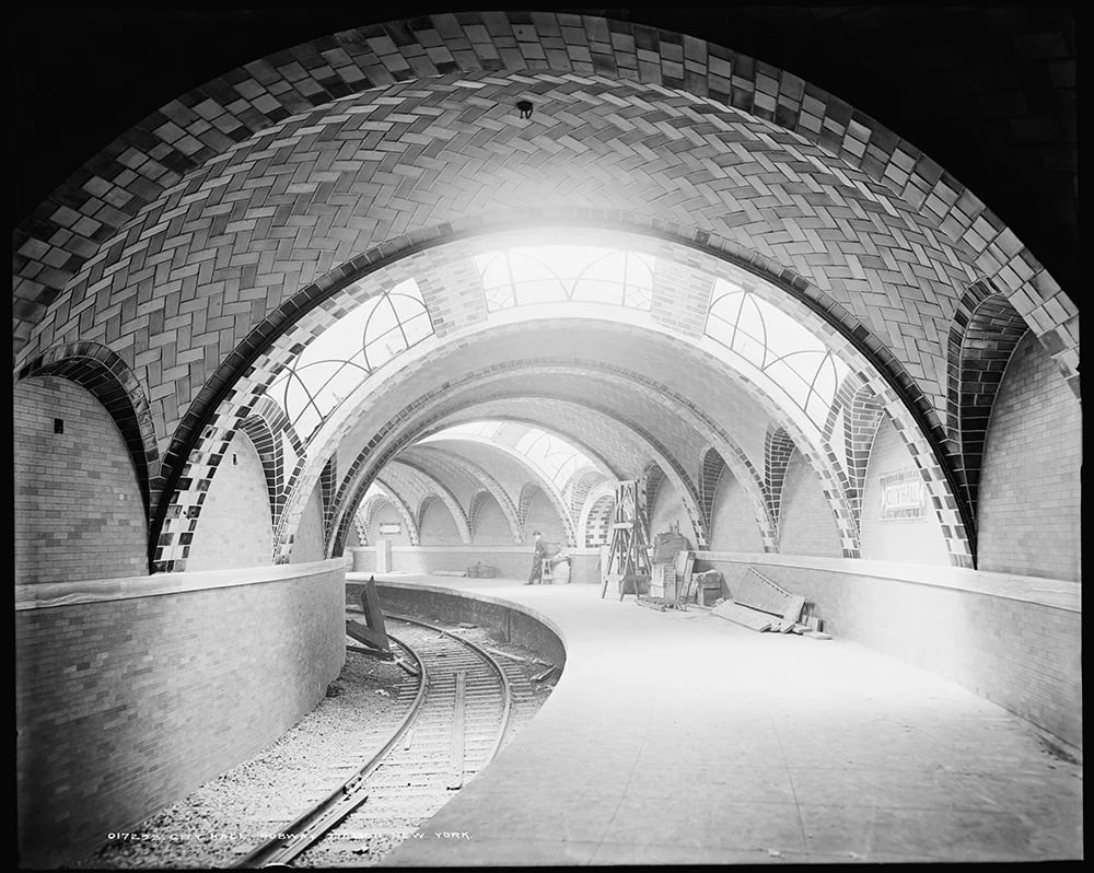 black and white photo of a subway station with a curving track
