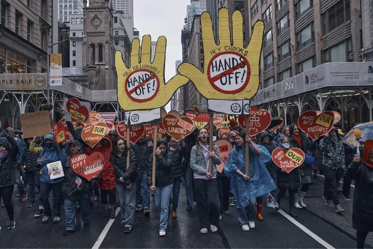 protesters holding signs marching down the street in NYC