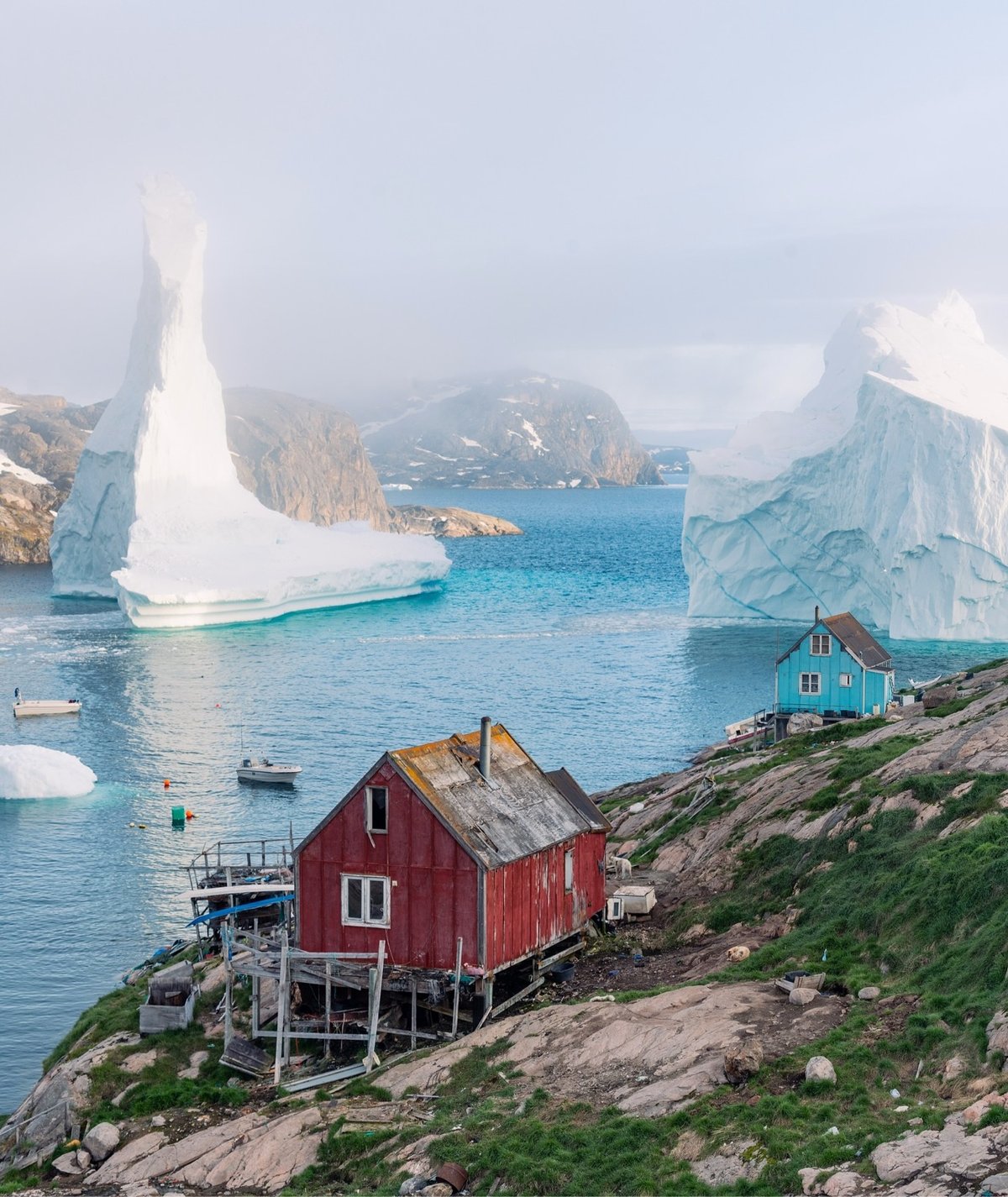 two icebergs just off the coast of a small village
