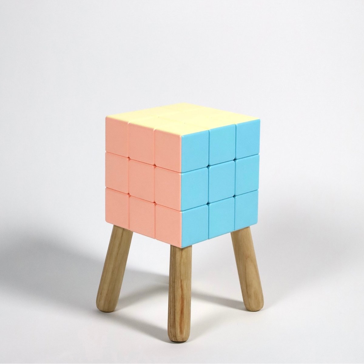 a small chair with four legs attached to a Rubik's Cube