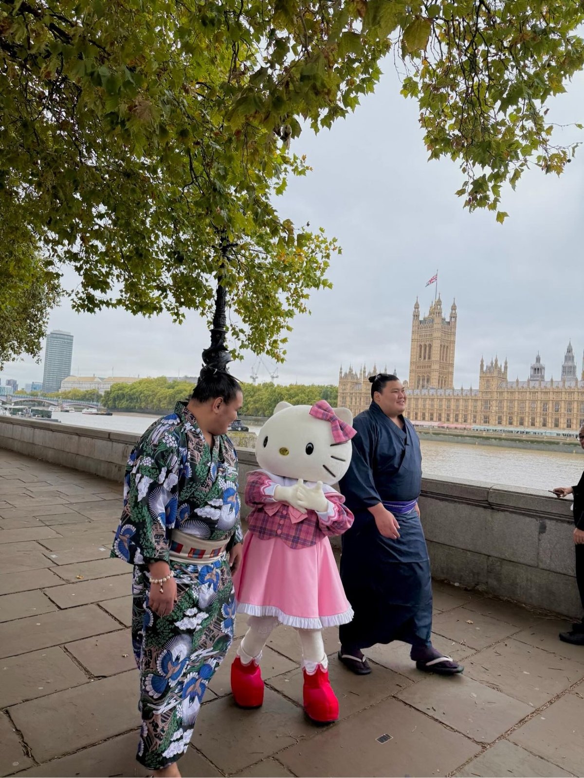 two sumo wrestlers walking in London with Hello Kitty