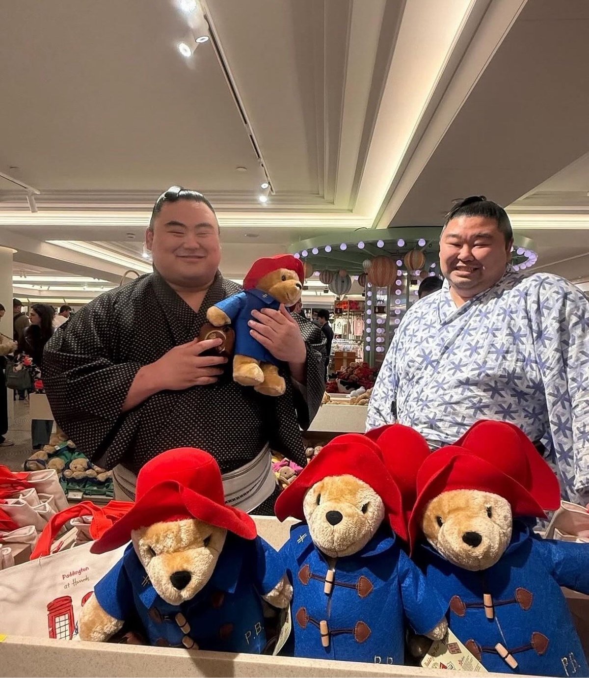 two sumo wrestlers posing with Paddington Bear
