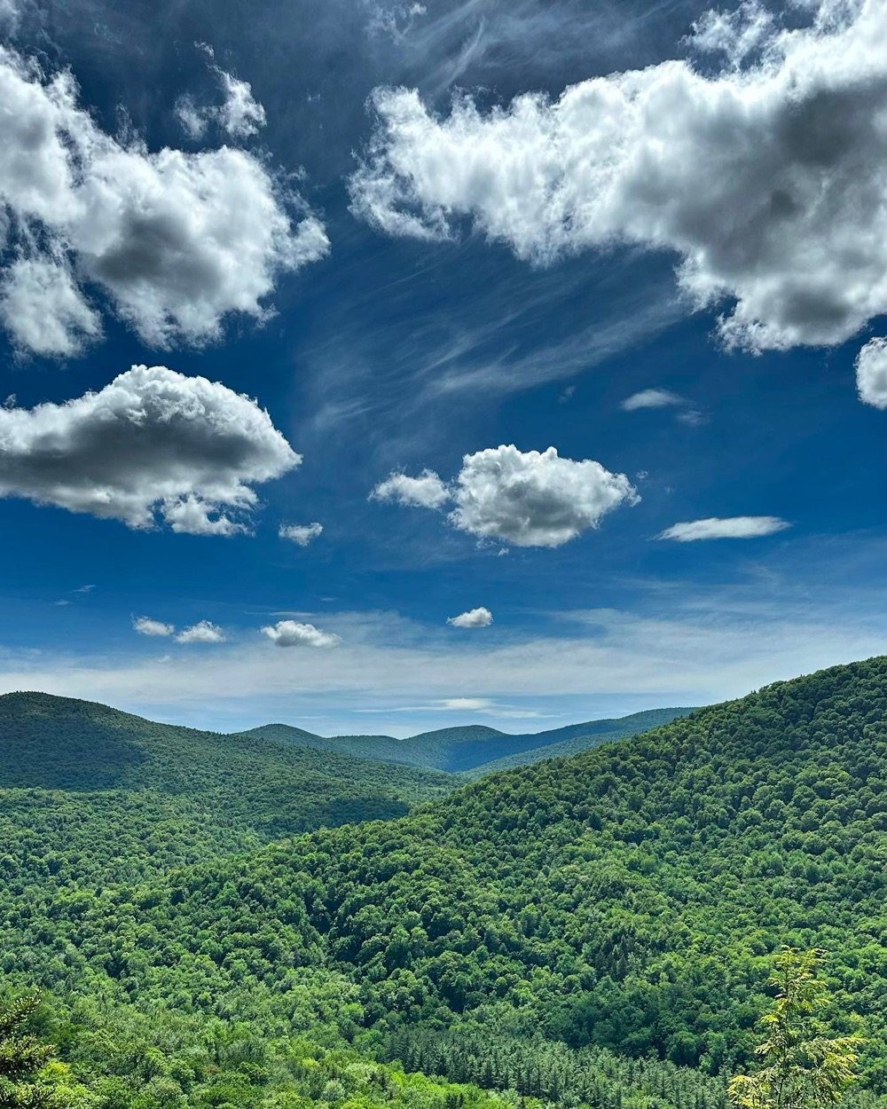 view of the green rolling hills of Vermont under a mostly sunny sky