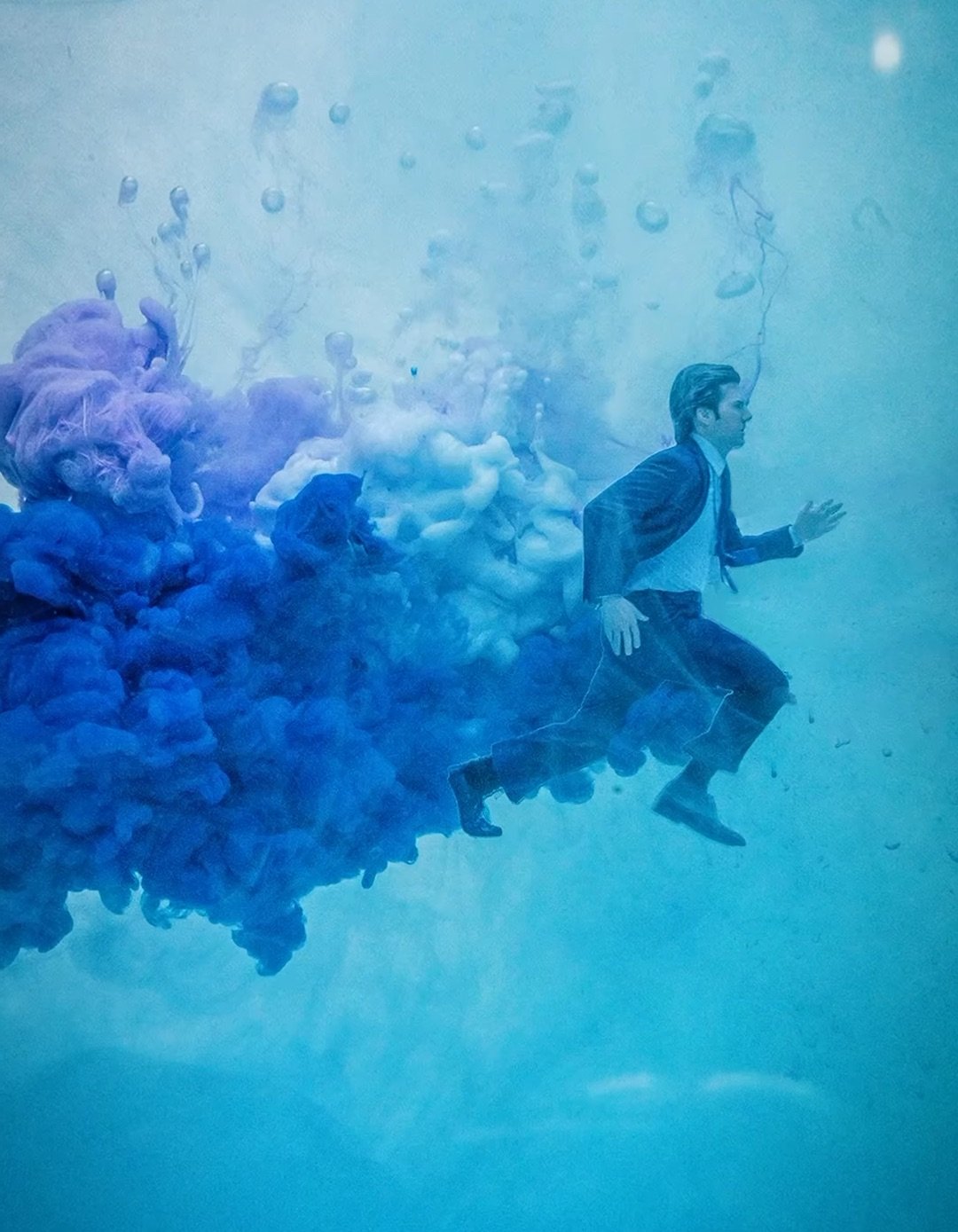 a man runs followed by a plume of blue smoke
