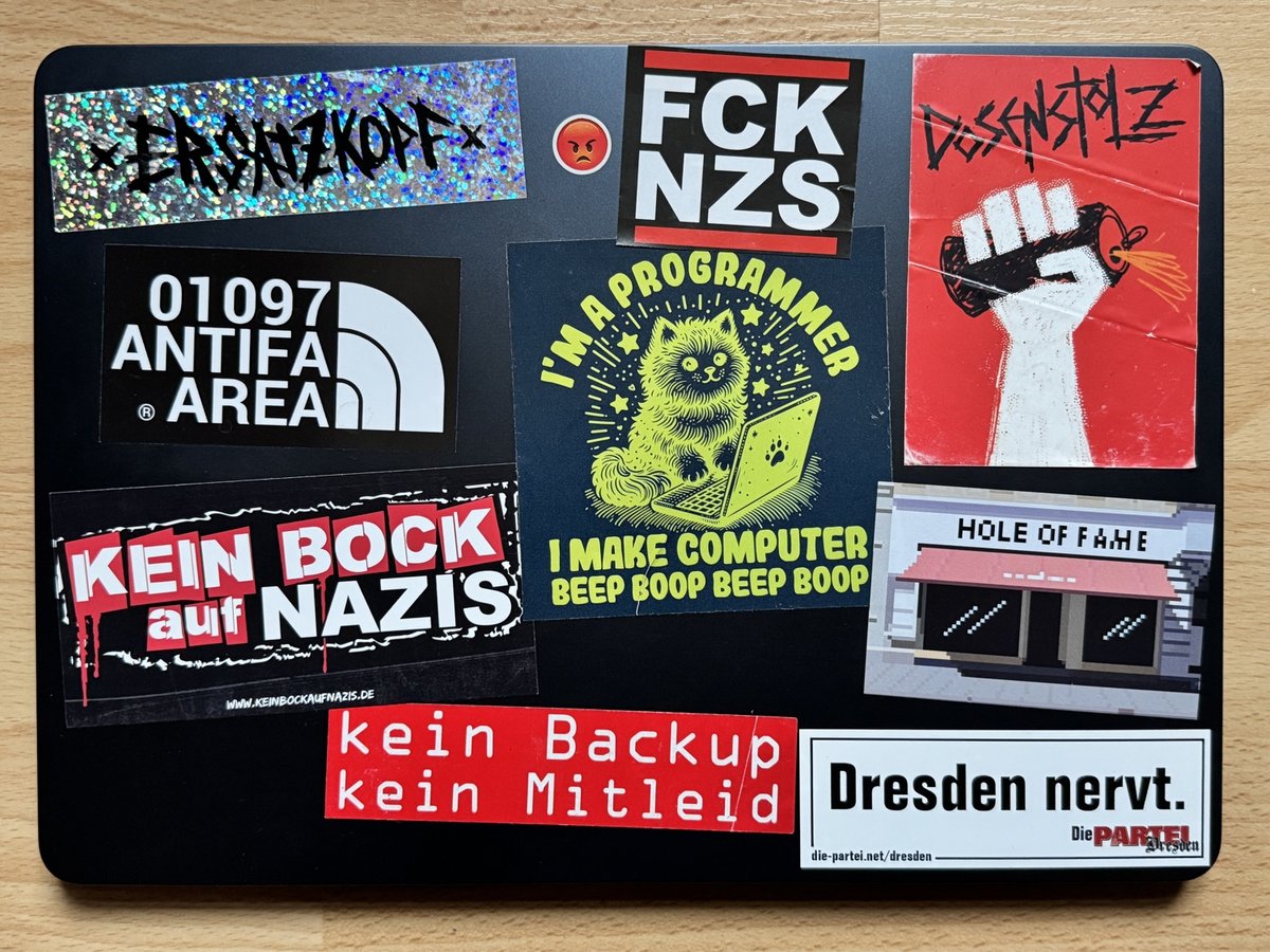 Black laptop covered with anti-Nazi and anti-fascist stickers including slogans, band logos, and political messaging.