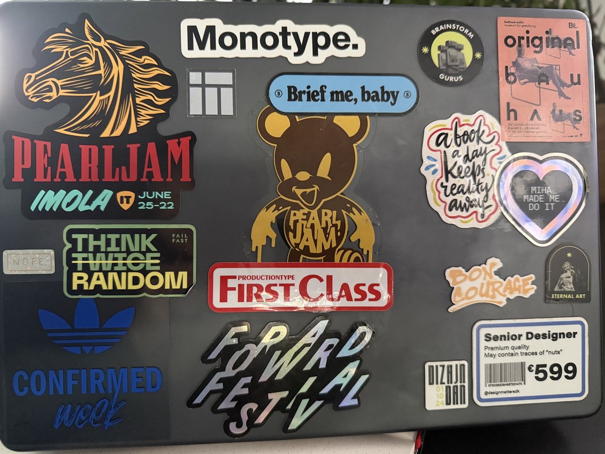 Laptop stickers featuring music and entertainment brands including Pearl Jam, Adidas, Brainstorm, and various band and designer logos on dark background.