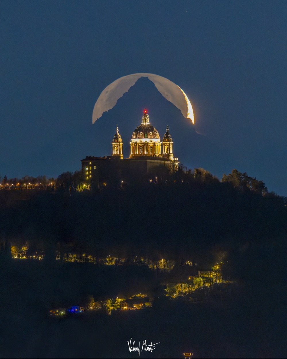 the Moon rising over a cathedral and a mountain, all three lined up perfectly