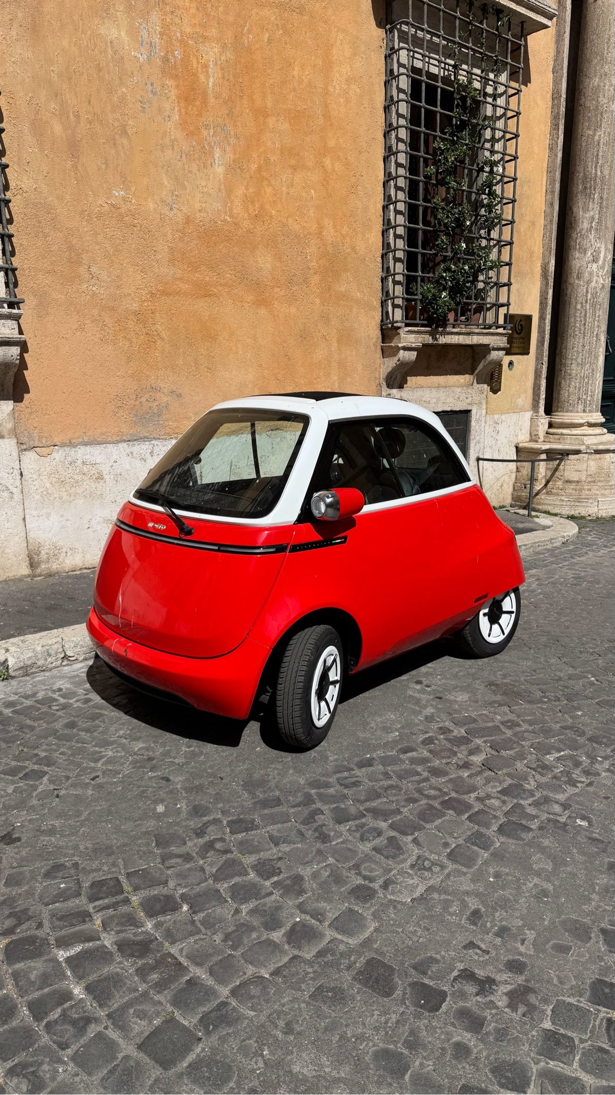 a bright red one-seater car on the streets of Rome
