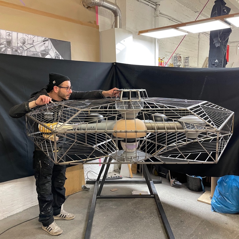 a model maker inspects a model alien spaceship