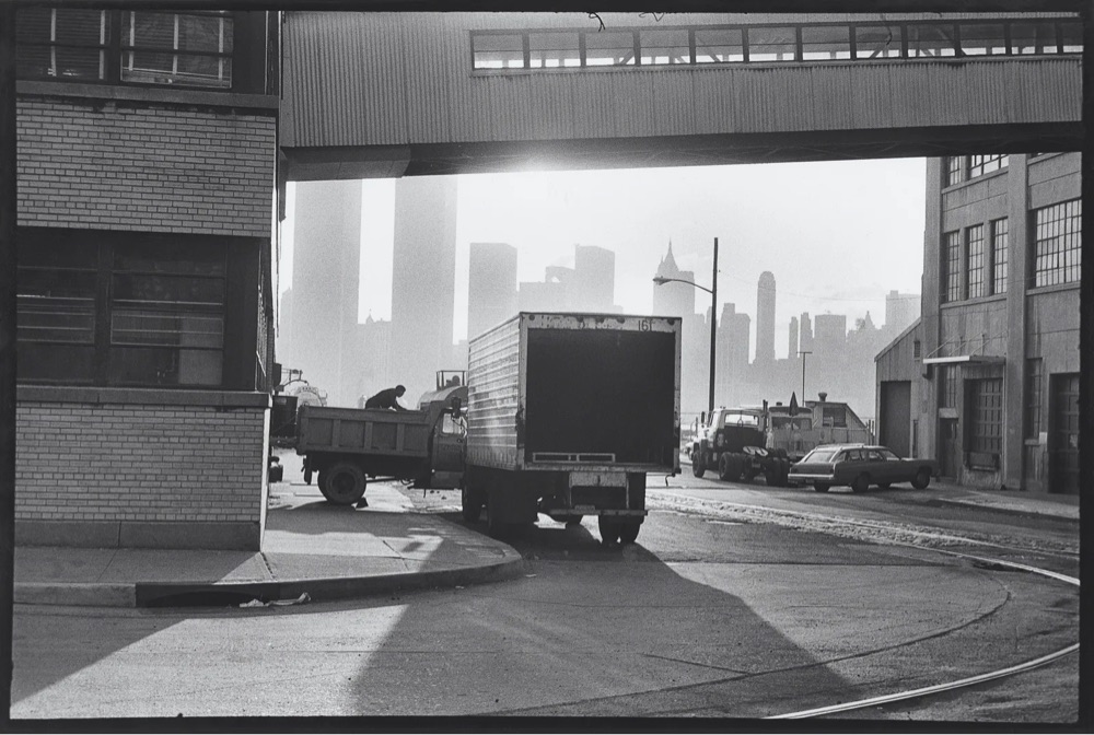 black and white photo of a big box truck under a bridge