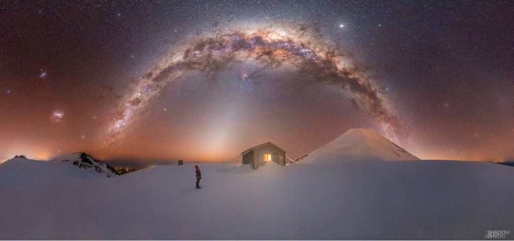 a photo of the Milky Way galaxy over a house in the snow